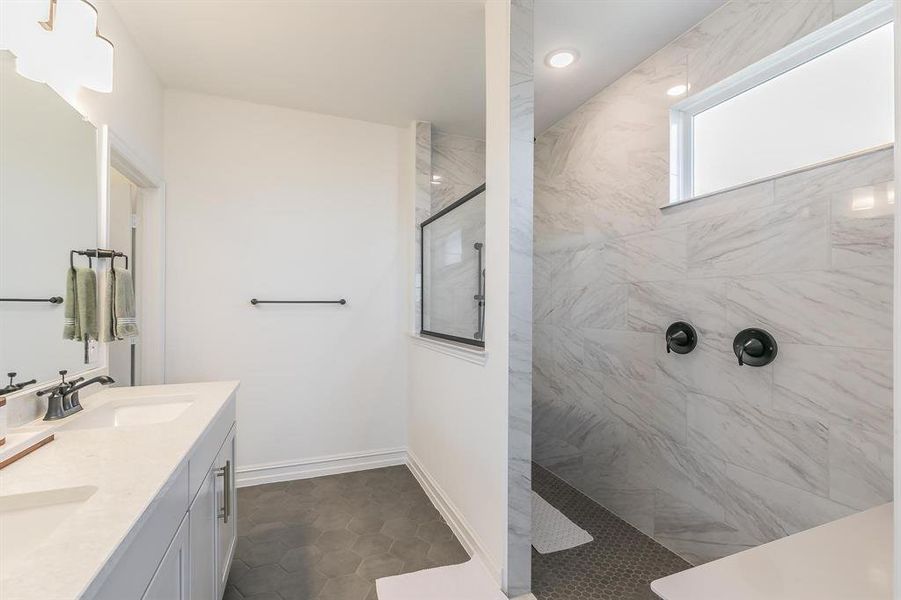 Bathroom featuring tile patterned floors, vanity, and tiled shower