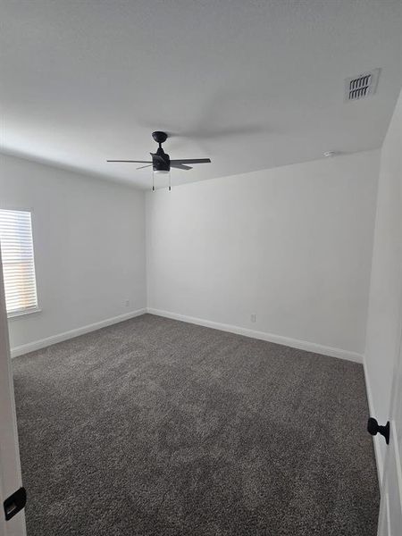 Spare room with dark colored carpet and a ceiling fan