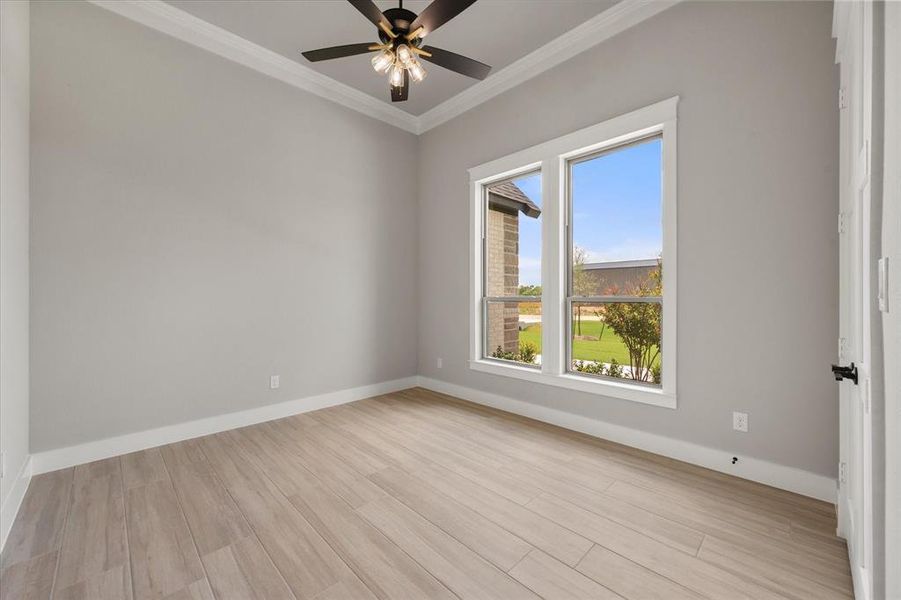 Room featuring wood-finish flooring, two large windows, a ceiling fan with integrated lighting, crown molding, and white baseboards