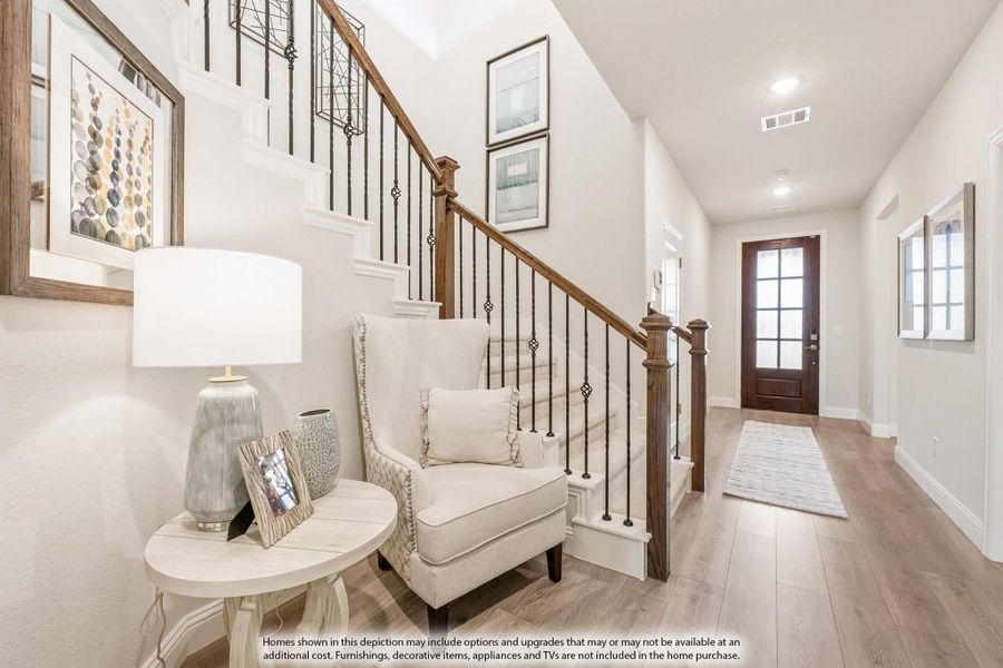 Bright entryway with wood and iron staircase, hardwood floors, and front door with glass panels
