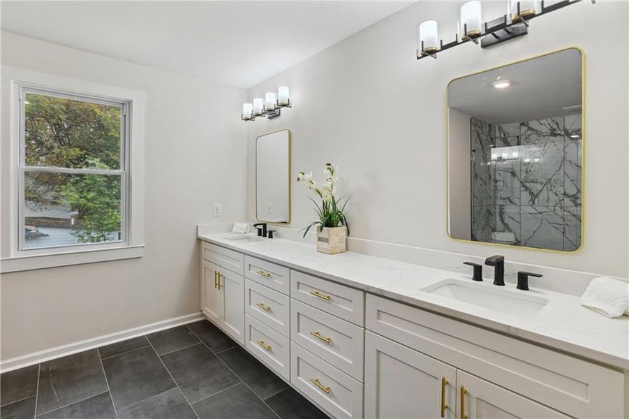 Bathroom featuring dual bowl vanity, tile flooring, and a tile shower