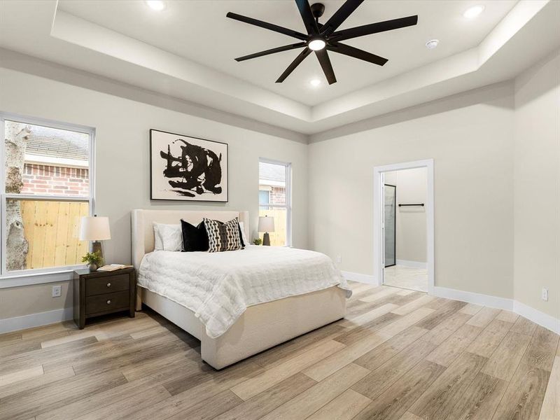 Bedroom with a tray ceiling, light wood-style floors, recessed lighting, and ceiling fan