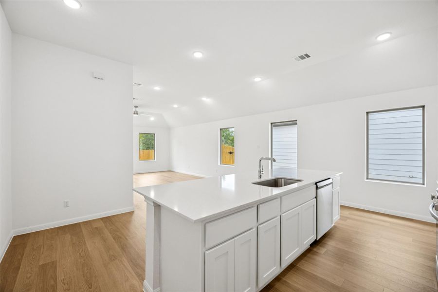Kitchen with white cabinets, light wood-type flooring, recessed lighting, a center island with sink, and open floor plan Kitchen with white cabinets, light wood-type flooring, recessed lighting, a center island with sink, and open floor plan