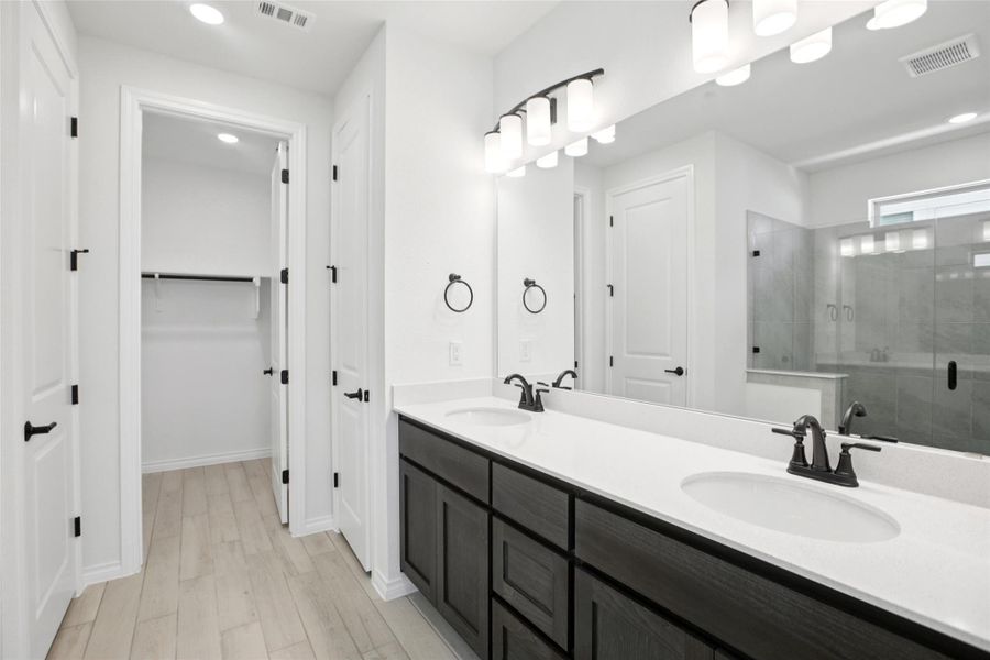 Bathroom with a shower stall, double vanity, a walk in closet, recessed lighting, and light wood-type flooring