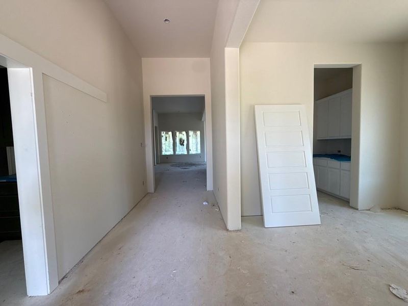 Unfinished interior hallway featuring light-toned walls and multiple doorways