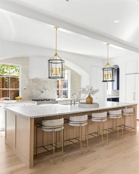 Kitchen featuring backsplash, a chandelier, white cabinets, a breakfast bar area, and beamed ceiling Kitchen featuring backsplash, a chandelier, white cabinets, a breakfast bar area, and beamed ceiling