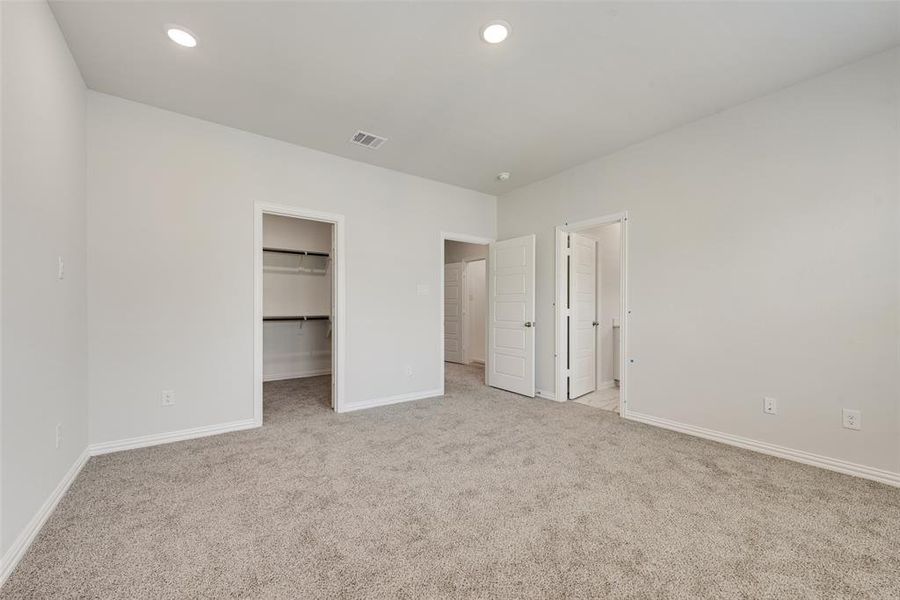 Unfurnished bedroom featuring a closet, light carpet, and a spacious closet