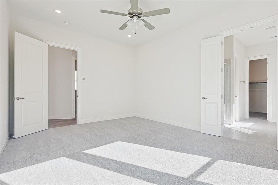 Bedroom with a walk in closet, light carpet, a closet, and ceiling fan