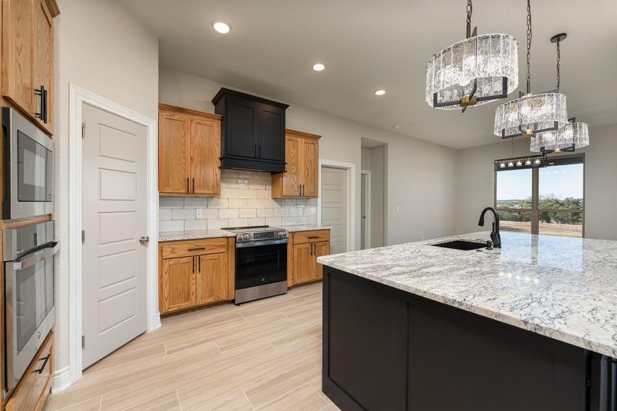 Kitchen with decorative backsplash, recessed lighting, brown cabinetry, light stone counters, and stainless steel appliances Kitchen with decorative backsplash, recessed lighting, brown cabinetry, light stone counters, and stainless steel appliances