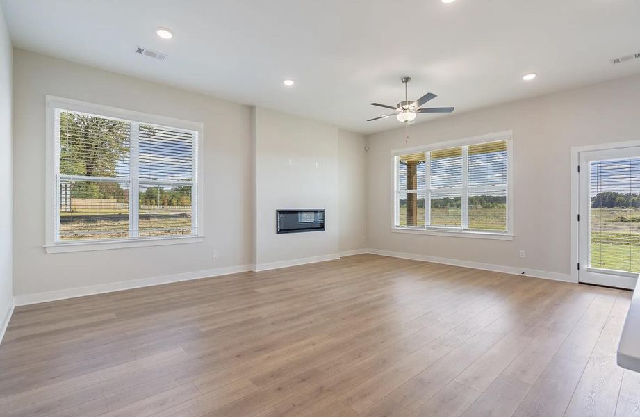 Spacious room featuring wood-finish flooring, an electric fireplace, multiple windows with horizontal blinds, recessed lighting, and a ceiling fan