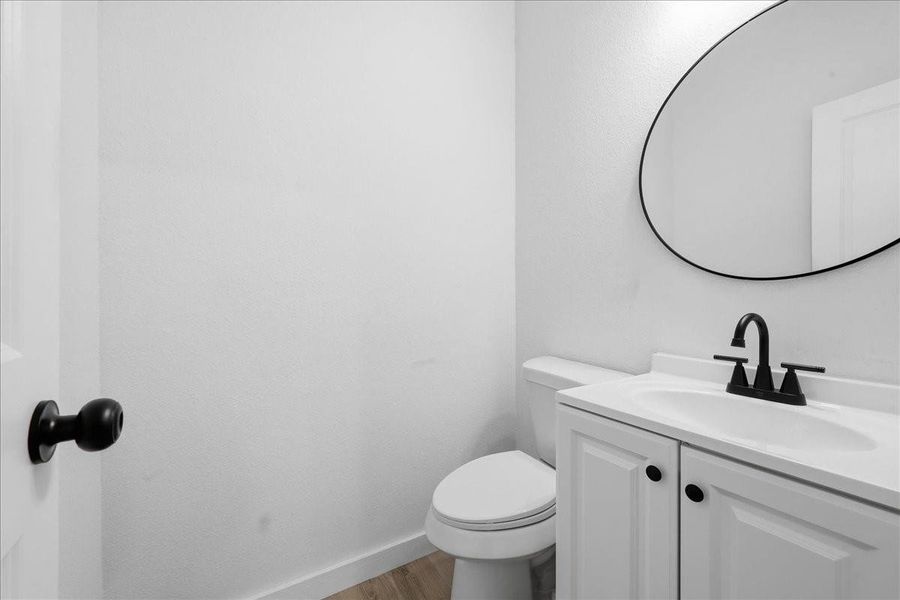 Convenient powder room/half bath featuring a modern vanity and round vanity mirror. Convenient powder room/half bath featuring a modern vanity and round vanity mirror.