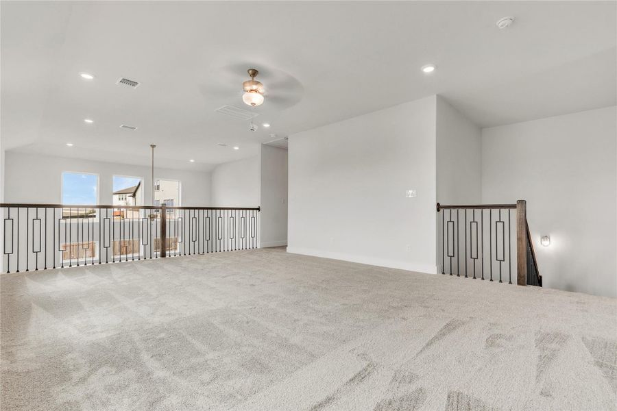 An airy loft area with plush carpet and modern railings overlooks the main living space.