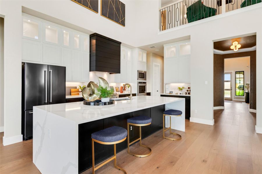 Kitchen with appliances with stainless steel finishes, a spacious island, light wood-type flooring, white cabinets, and a breakfast bar Kitchen with appliances with stainless steel finishes, a spacious island, light wood-type flooring, white cabinets, and a breakfast bar