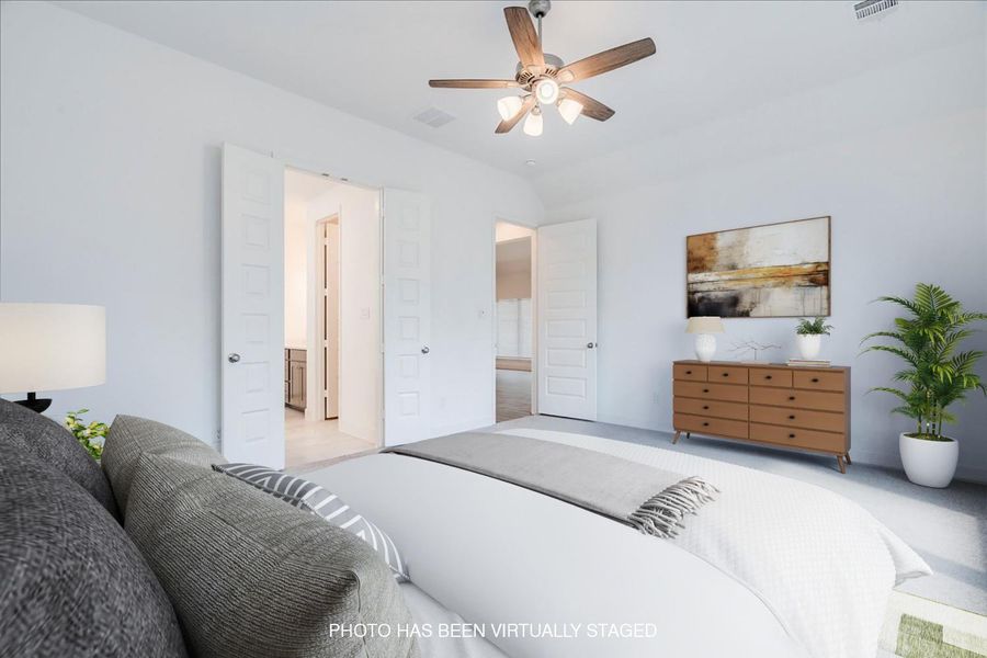 Spacious bedroom featuring light-colored carpeting, white walls, and a ceiling fan with integrated lighting