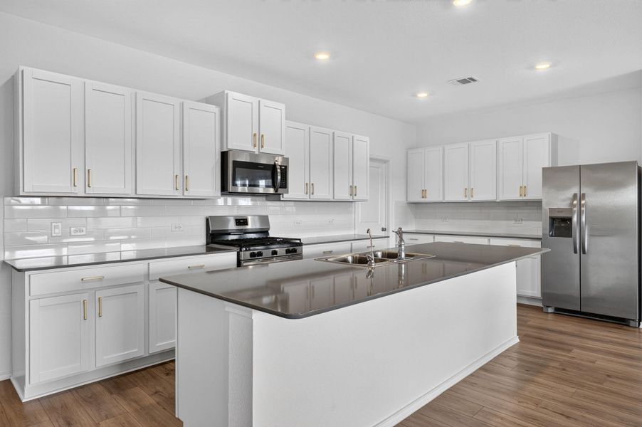 A well-lit kitchen with sleek white cabinetry, stainless steel appliances, and an inviting center island with a double sink. A well-lit kitchen with sleek white cabinetry, stainless steel appliances, and an inviting center island with a double sink.