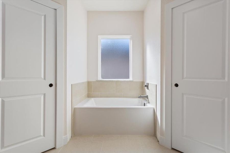 Full bathroom featuring a garden tub and light tile patterned floors