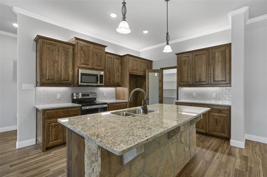 Kitchen with appliances with stainless steel finishes, crown molding, dark wood-type flooring, and backsplash