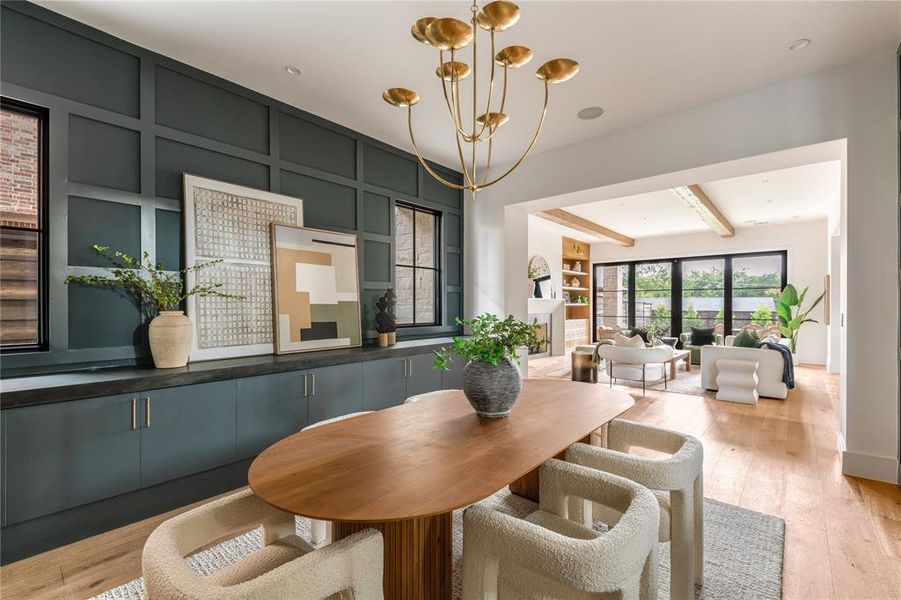 Dining area featuring a chandelier, beamed ceiling, light wood finished floors, and built in features
