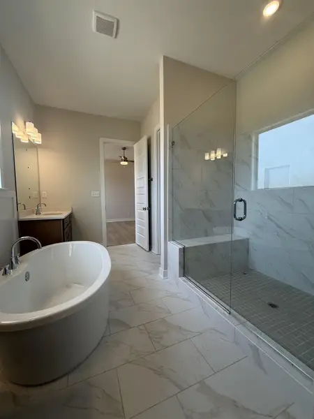 Full bath featuring a soaking tub, light marble finish floors, vanity, and a marble finish shower