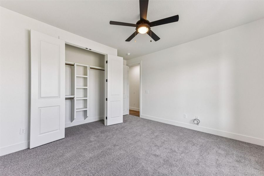 Unfurnished bedroom with light carpet, a ceiling fan, and a closet
