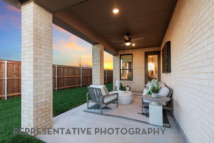 A covered patio with brick pilars creates a charming, shaded space to gather, relax, and enjoy the outdoors.