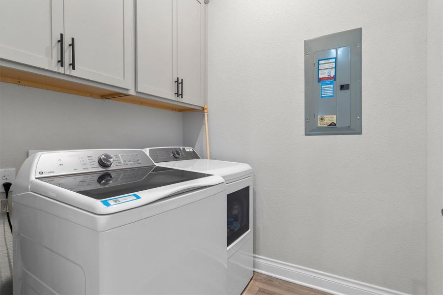 Functional utility space includes built-in upper cabinetry and sleek modern laundry appliances.
