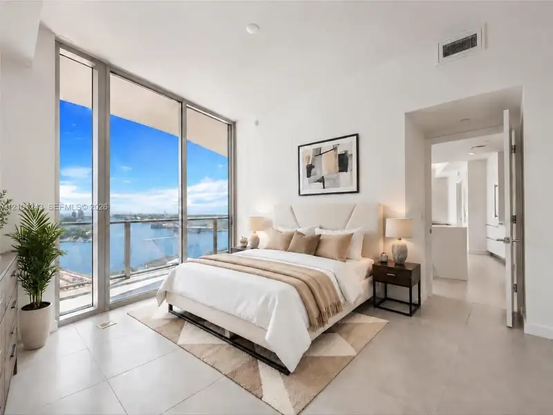 Floor-to-ceiling windows, porcelain tile flooring, and integrated balcony access featuring metal and glass railing Floor-to-ceiling windows, porcelain tile flooring, and integrated balcony access featuring metal and glass railing