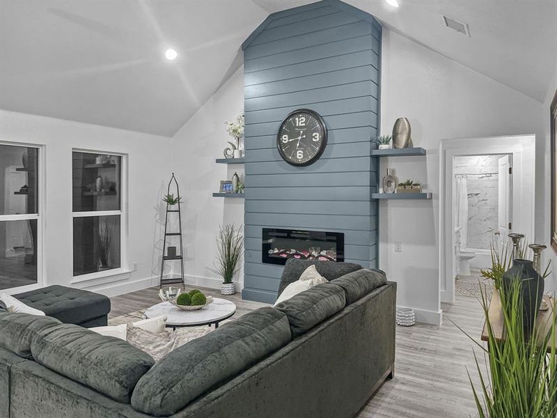 Living room featuring a large fireplace, vaulted ceiling, and light wood-type flooring