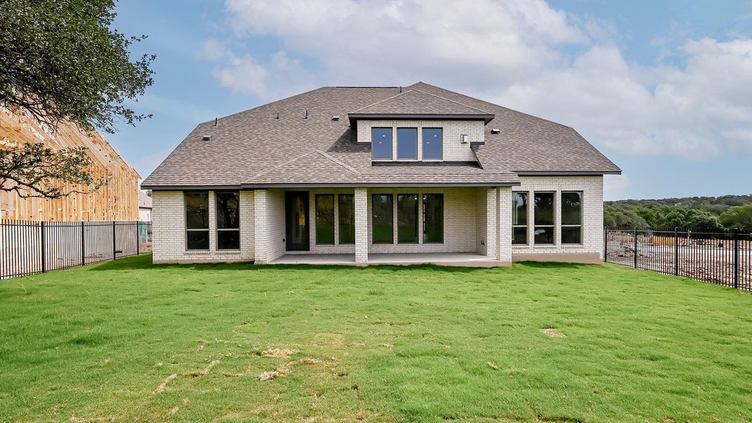 Back of property featuring brick siding, a shingled roof, and a patio area