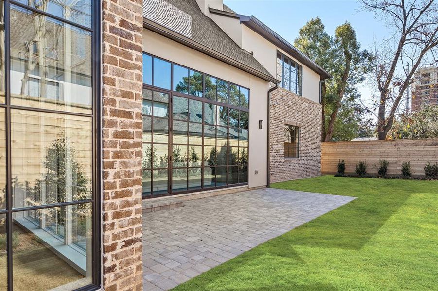 Seamlessly extending from the family room and framed by a stylish privacy fence and landscaped greenery, this expansive patio and backyard create the perfect setting for outdoor relaxation and entertaining. Just beyond the striking wall of windows, the paved patio offers ample space for seating or dining, while the lush, manicured lawn provides a serene retreat.