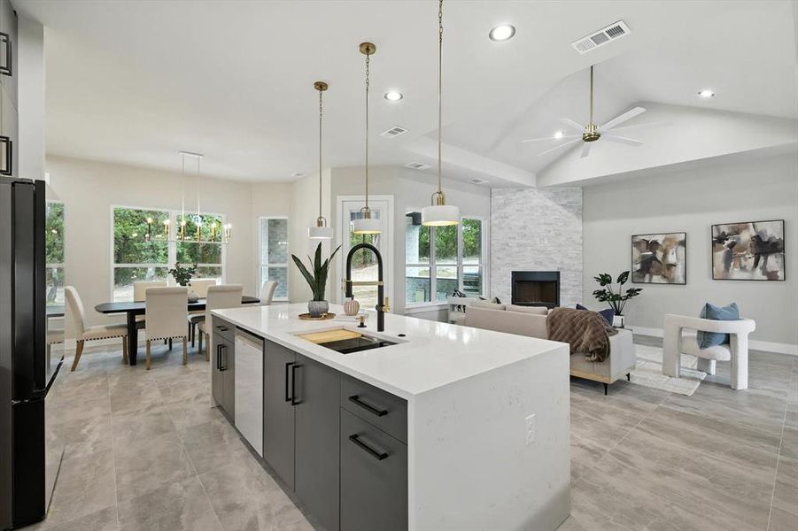 Kitchen featuring pendant lighting, freestanding refrigerator, an island with sink, open floor plan, and a fireplace