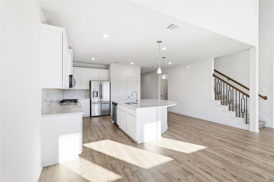 Kitchen featuring a center island with sink, white cabinetry, pendant lighting, stainless steel appliances, and recessed lighting
