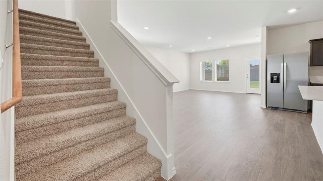 Stairway with wood finished floors and recessed lighting