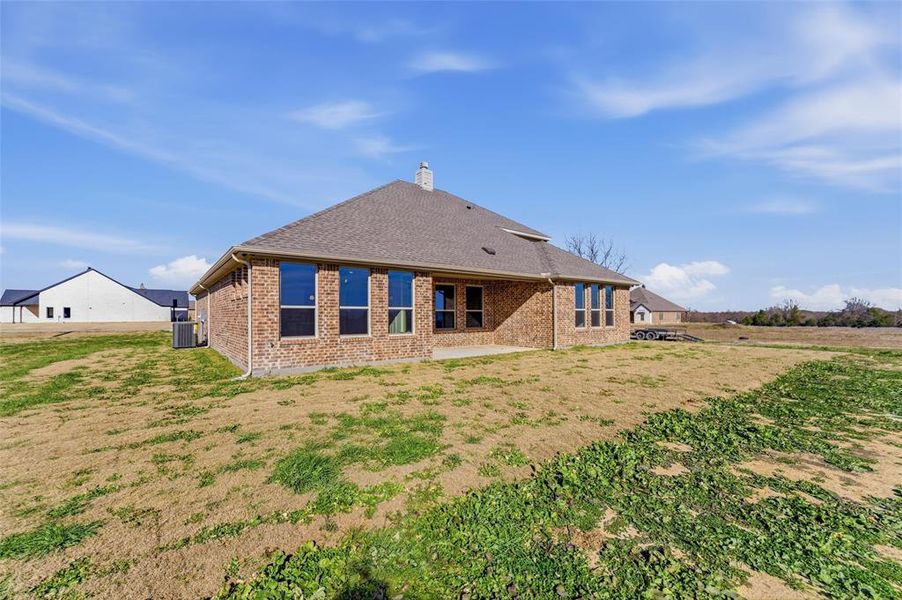 Rear view of property with brick siding, a yard, a chimney, and a patio