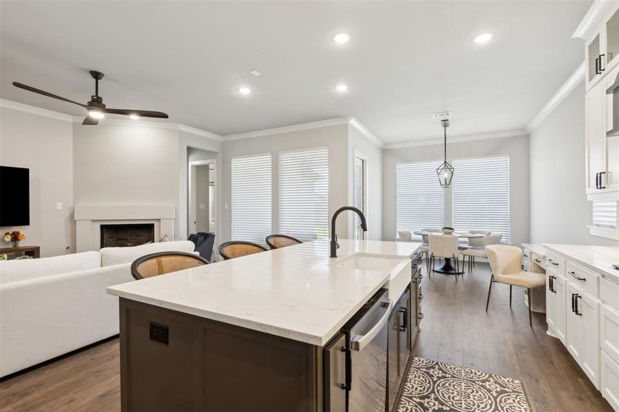 Kitchen featuring pendant lighting, a center island with sink, sink, crown molding, and dark hardwood / wood-style flooring