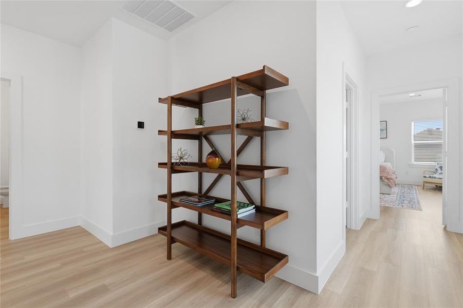 Hallway featuring light wood-finish flooring and bright white walls