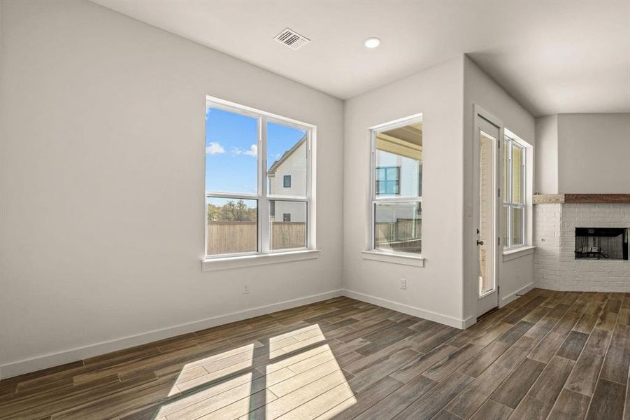 Unfurnished living room featuring dark wood-style floors, baseboards, a brick fireplace, and recessed lighting
