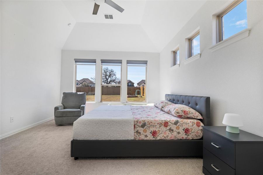 A tranquil bedroom with vaulted ceilings and ample natural light from generously sized windows. A tranquil bedroom with vaulted ceilings and ample natural light from generously sized windows.