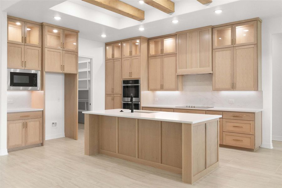 A grand central island anchors this naturally illuminated kitchen, featuring abundant cabinetry and sleek appliances. A grand central island anchors this naturally illuminated kitchen, featuring abundant cabinetry and sleek appliances.
