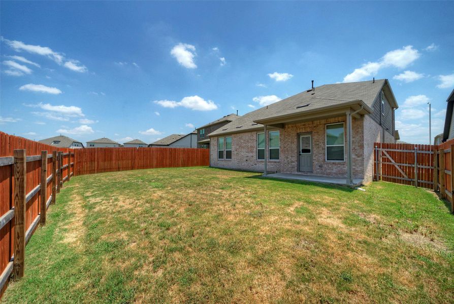 A spacious backyard provides ample green space, enclosed by privacy fencing and featuring a covered patio for outdoor enjoyment. A spacious backyard provides ample green space, enclosed by privacy fencing and featuring a covered patio for outdoor enjoyment.