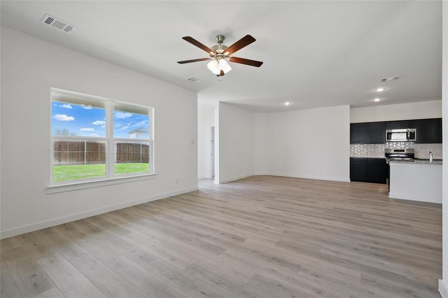 Unfurnished living room with light wood-type flooring, baseboards, a ceiling fan, and visible vents Unfurnished living room with light wood-type flooring, baseboards, a ceiling fan, and visible vents