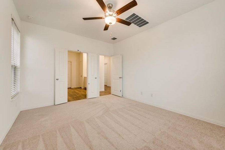 Unfurnished bedroom with ceiling fan and light carpet