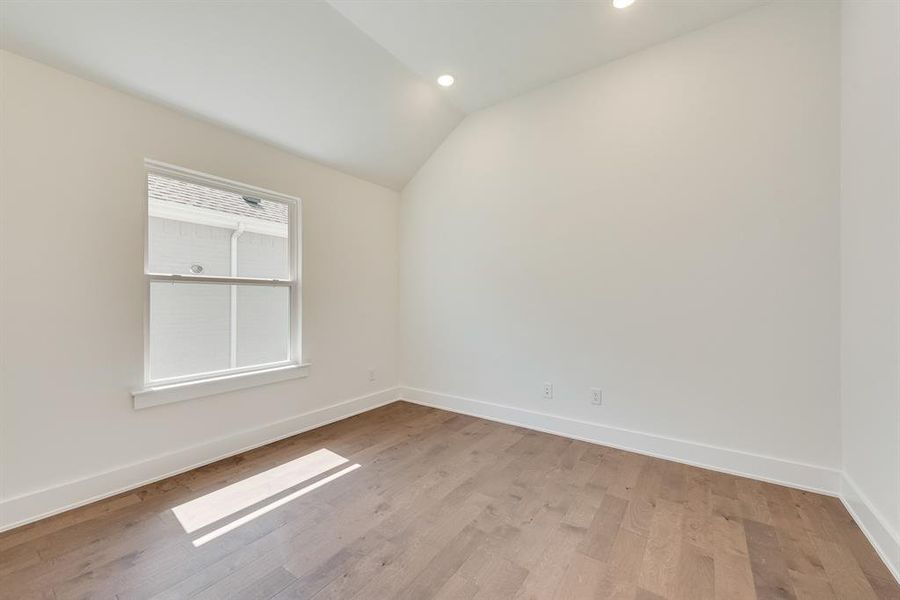 Empty room with vaulted ceiling, wood finished floors, and recessed lighting Empty room with vaulted ceiling, wood finished floors, and recessed lighting