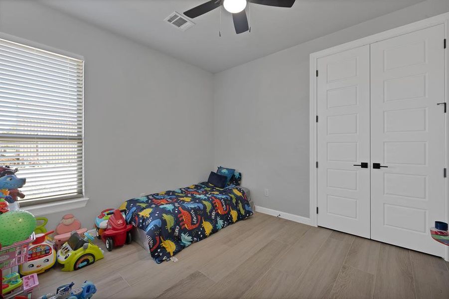 Bedroom featuring a closet, visible vents, a ceiling fan, wood finished floors, and baseboards