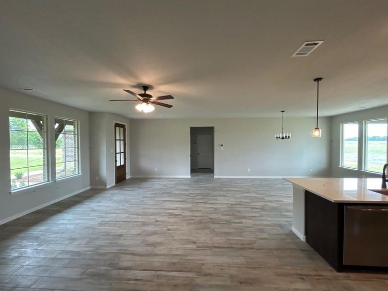 Expansive open-concept living area featuring wood-finish flooring, numerous windows, a contemporary ceiling fan, and recessed lighting Expansive open-concept living area featuring wood-finish flooring, numerous windows, a contemporary ceiling fan, and recessed lighting