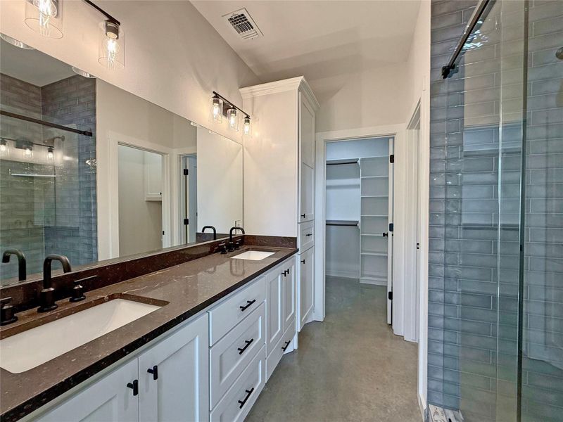 Primary Full bath featuring a spacious closet, polished concrete flooring, a stall shower, and double vanity