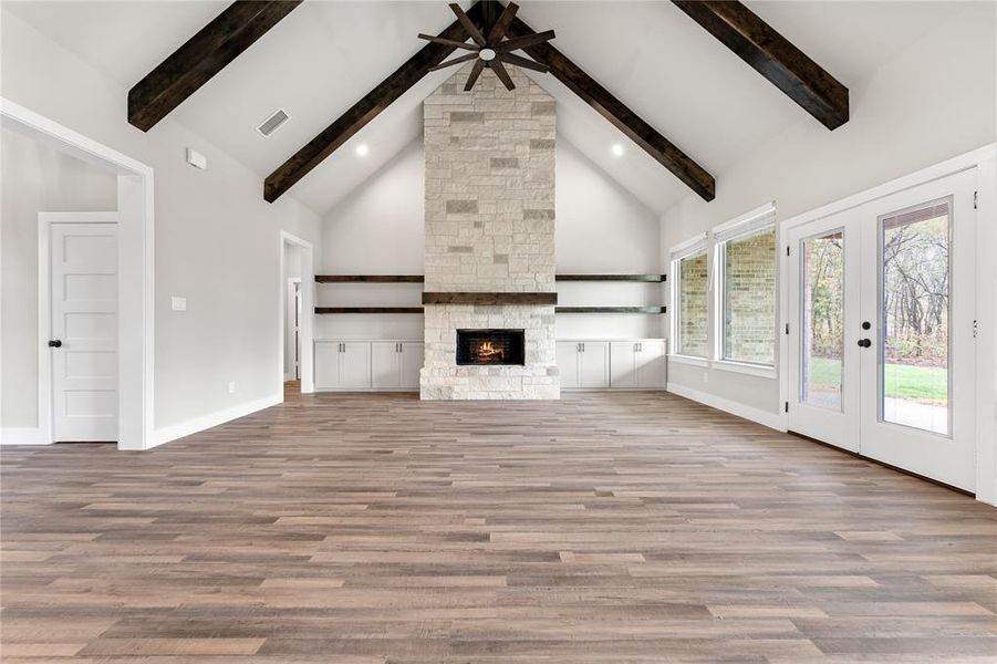 Unfurnished living room with a fireplace, wood-type flooring, and beamed ceiling