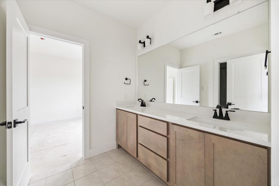 One of the 3 secondary bathrooms. The cabinetry and style choices remain consistent throughout the home, lending a serene feel. One of the 3 secondary bathrooms. The cabinetry and style choices remain consistent throughout the home, lending a serene feel.