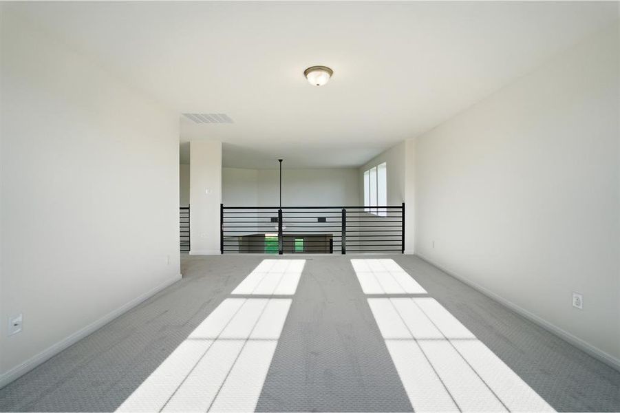 Spacious loft area featuring light gray carpeting and white walls