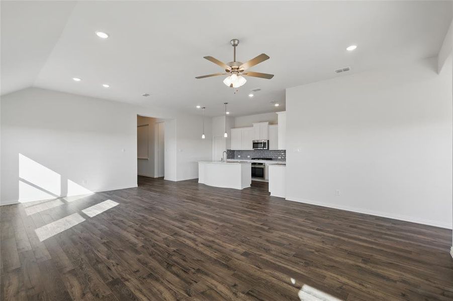 Unfurnished living room with a ceiling fan, recessed lighting, and dark wood-type flooring